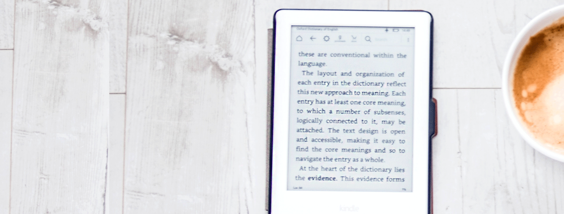 Ebook and cup of coffee on white plank surface