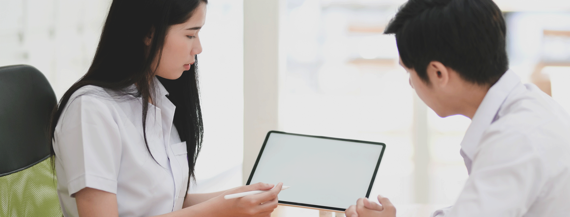 Young woman showing young man something on a tablet