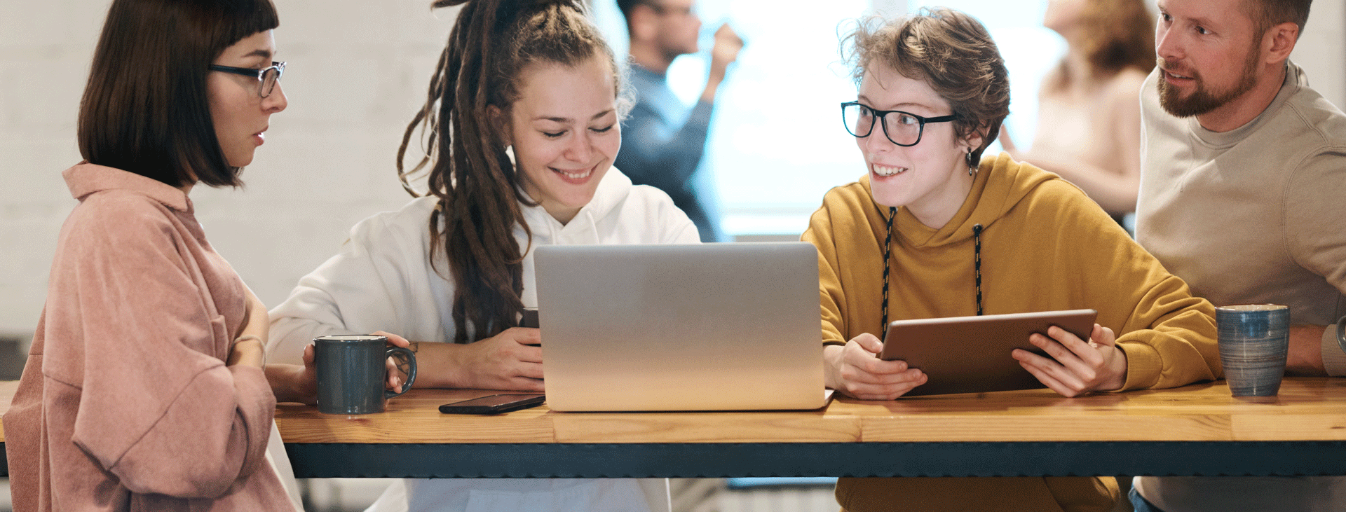 Four young people meeting with coffee, laptop and tablet