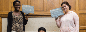 Two students holding chalk boards declaring their dream jobs: architect and to do good in the world